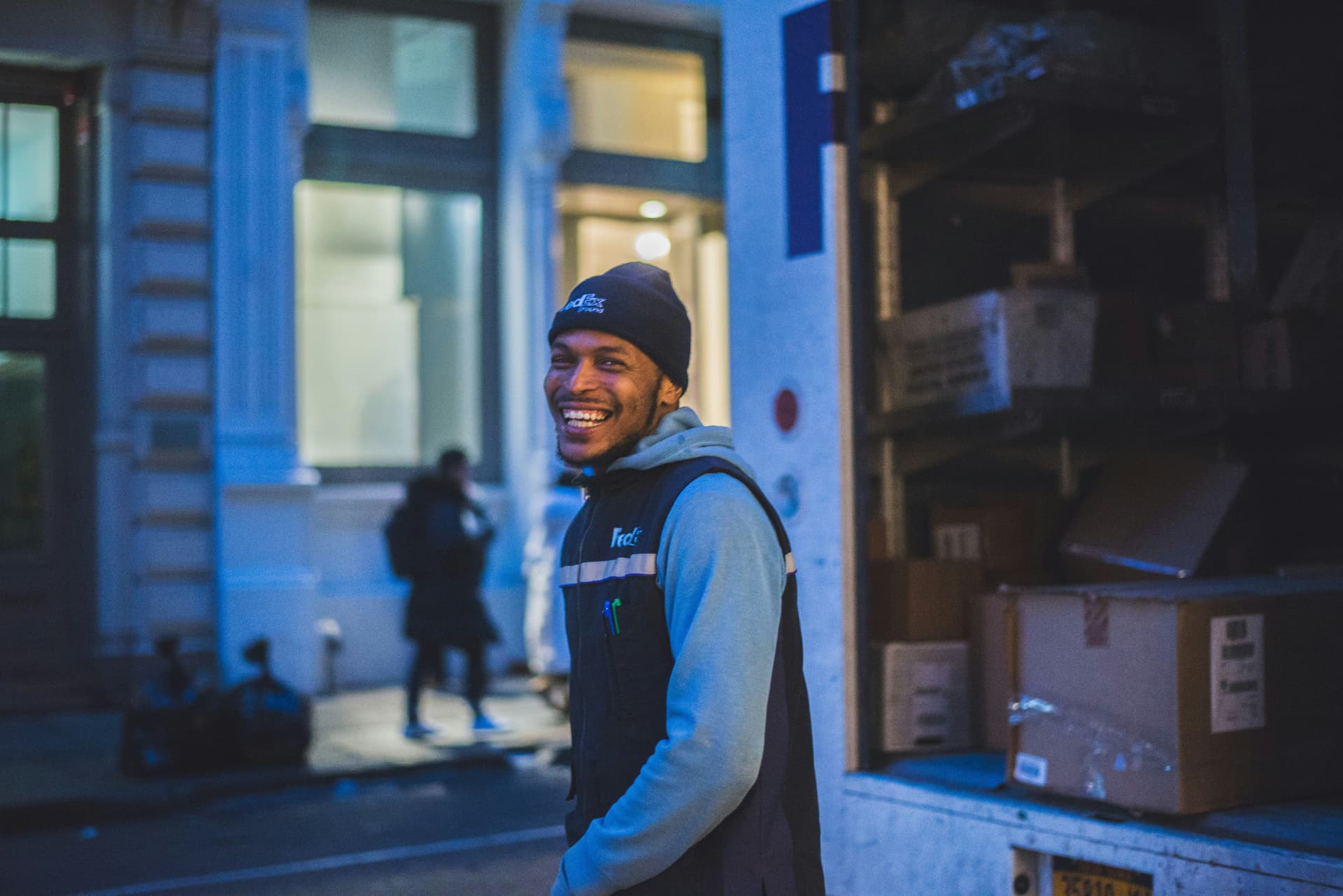 A self-employed courier smiling beside his delivery van at dusk