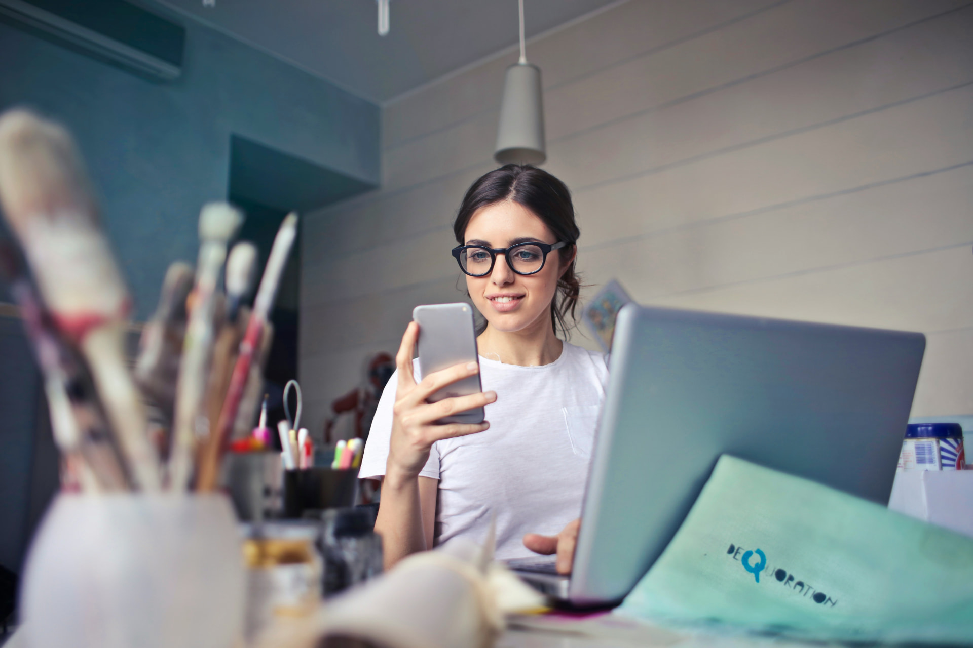 A self-employed woman checking her phone at a creative workspace